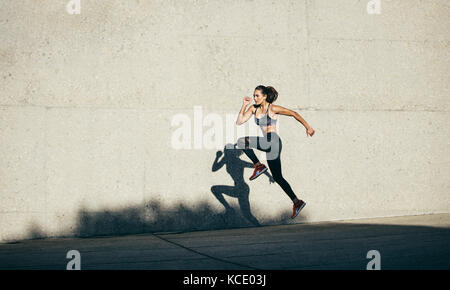 Healthy young woman running and jumping outdoors. fitness model exercising in morning outdoors. Stock Photo