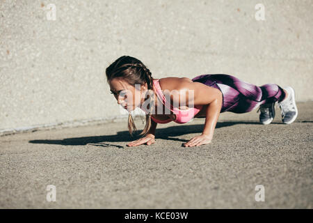 Healthy and muscular young woman doing pushups outdoors. fitness female doing core exercise in morning. Stock Photo