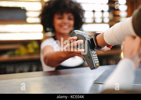 Customer making wireless or contactless payment using smartwatch. Cashier accepting payment over nfc technology. Stock Photo