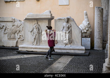 Rome. Italy. Visitor looking at reliefs from the Temple of Hadrian in the courtyard of Palazzo dei Conservatori, Capitoline Museums. Stock Photo