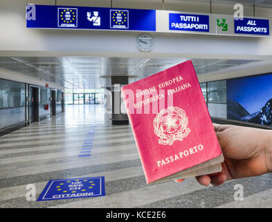 Person holding Italian passport in airport passport control area, digital composite Stock Photo