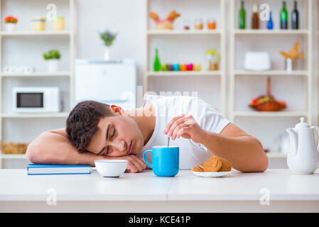 Man falling asleep during his breakfast after overtime work Stock Photo