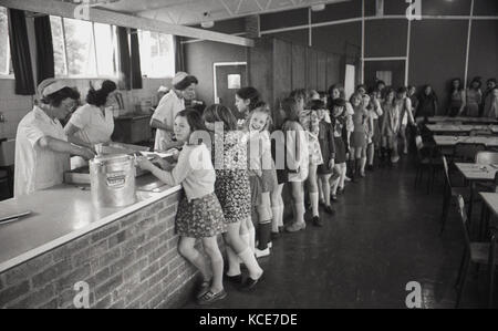 1970s, historical picture showing young girls at Langbourne Primary School queuing up inside for their school dinner (lunch), Dulwich, London, SE21, England, UK. Stock Photo