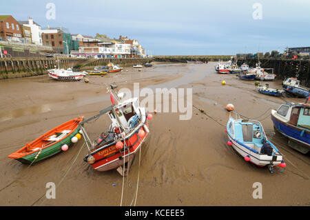 Various small boats lying on the sand in Bridlington harbour at low tide. Bridlington, East Yorkshire. January. Stock Photo