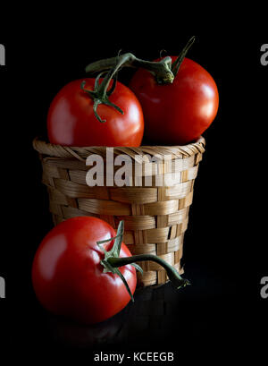 Fresh tomatoes in basket on black background Stock Photo