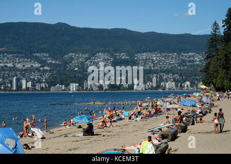 People bath in the glorious sunshine on a sunny summer day on Third Beach in Vancouver, British Columbia, Canada. Stock Photo