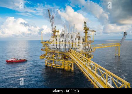 Oil and gas central processing platform in the gulf of Thailand. Construction crane transfer cargo to boat. Stock Photo