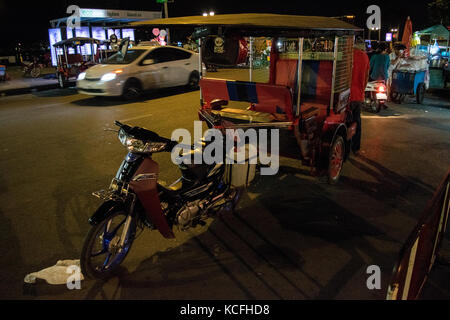 A pink tuk-tuk parked next to the Phnom Penh night market. Waiting for tourists in a busy road, close to Tonle Sap river, Cambodia, South East Asia Stock Photo