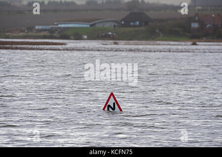 View across Cley Marshes from West Bank with Coastguards road sign submerged  North Norfolk coast flooded after Friday January 13th 2017 North Sea sur Stock Photo