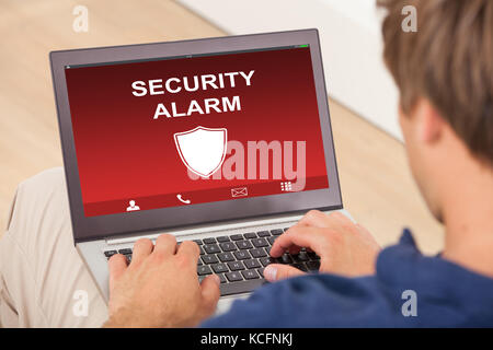 Close-up Of A Man Using Laptop Showing Security Alarm On Screen Stock Photo