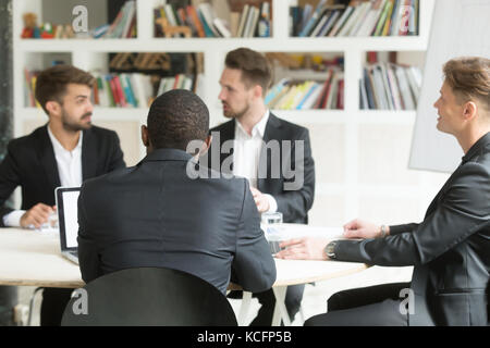 Multiethnic team of male coworkers discussing corporate plans during briefing. Businessmen having discussion about investment opportunities, new busin Stock Photo