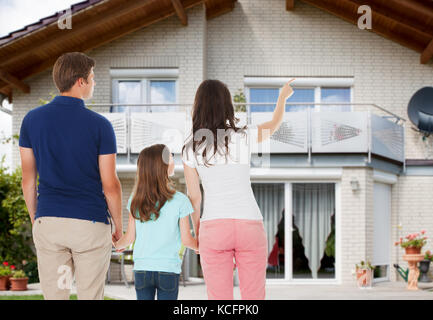 Rear View Of A Family Standing In Front Of Their New Home Stock Photo