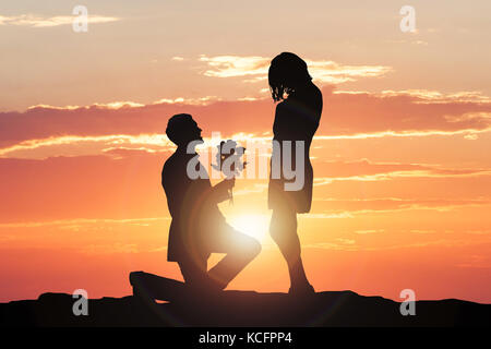 Silhouette Of A Man Making Proposal To Woman During Sunset Stock Photo