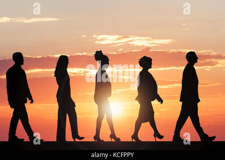 Silhouette Of Multiethnic People Walking At Sunset Stock Photo