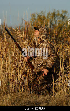 A duck hunter in camouflage calls ducks from a marsh in South Texas Stock Photo