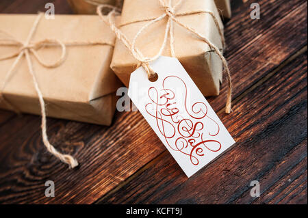 Two gift boxes and tag with Big Sale text on kraft paper and wooden background. Hand written calligraphy and lettering Stock Photo