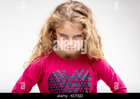 Portrait of preteen sulky girl making angry face against plain background Stock Photo