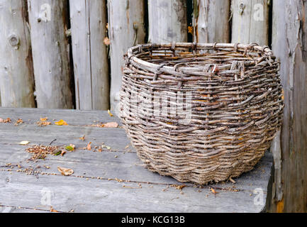 Big beautiful wicker basket stands on a wooden table in the fall. Preparing for harvesting and selling it. Stock Photo