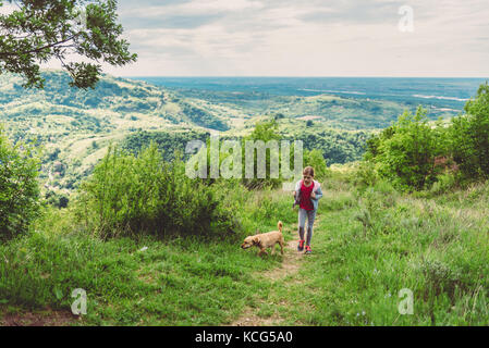 Girl and her dog walking along a hiking trail Stock Photo