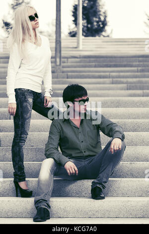 Young fashion couple in sunglasses on the steps Stock Photo