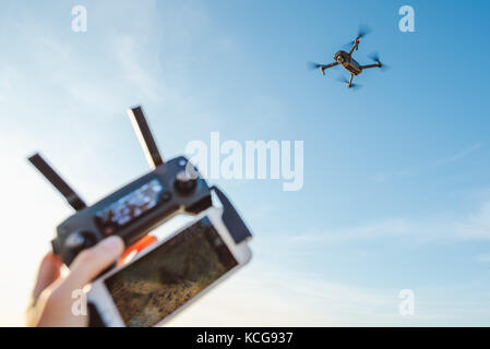 Man hand holding remote controller and using quad copter on natural background Stock Photo