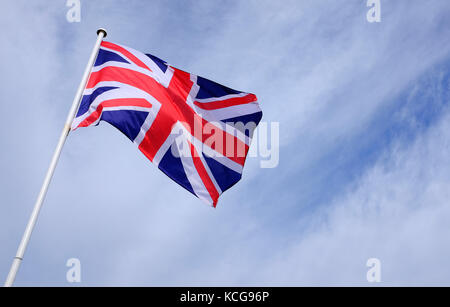 union jack flag flying on blue sky background Stock Photo