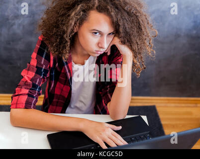 Indisposed teenage girl sitting in front of laptop computer at home Stock Photo