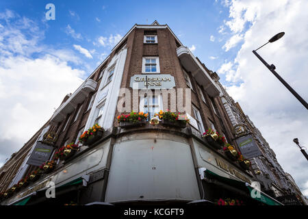 Horizontal picture upwards of a brick building with cloudy sky and flowers located in London. Stock Photo