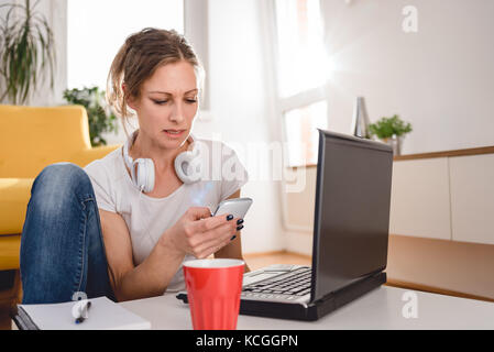 Woman wearing white shirt sitting at the coffee table and using smart phone at home Stock Photo