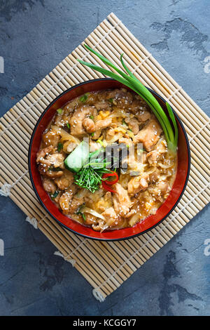 Oyakodon Japanese rice on topped with chicken, egg, onion, and seaweed in ceramic rice bowl Stock Photo