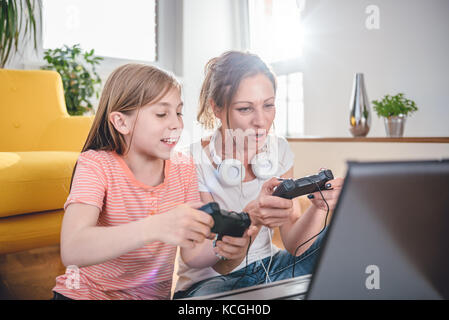 Mother and daughter playing video games on laptop at home Stock Photo