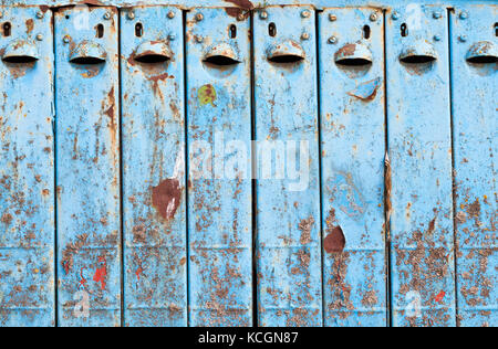 Old blue mailbox for several houses. The box is made of metal and painted with blue paint. Iron began to rust and paint Stock Photo