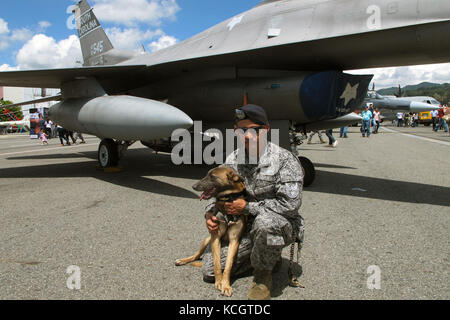 A Colombian Air Force K-9 handler poses with his military working dog in front of a South Carolina Air National Guard F-16 during the Colombian Air Force’s Feria Aeronautica Internaccional – Colombia in Rionegro,  July 14, 2017. The United States Air Force is participating in the four-day air show with two South Carolina Air National Guard F-16s as static displays, plus static displays of a KC-135, KC-10, along with an aerial demonstration by the Air Combat Command’s Viper East Demo Team and a B-52 flyover. The United States military participation in the air show provides an opportunity to str Stock Photo