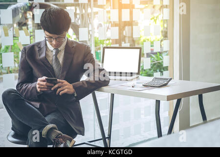 Portrait of young business man using smart phone working analyzing report in an office Stock Photo