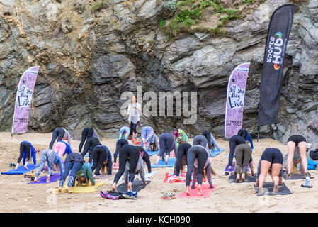A womens group practising yoga on a beach - Surf Betty's Festival a festival held in Newquay empowering women through fitness and surfing. Stock Photo