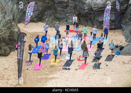 A womens' group practising yoga on a beach - Surf Betty's Festival a womens' festival held in Newquay empowering women through fitness and surfing. Stock Photo
