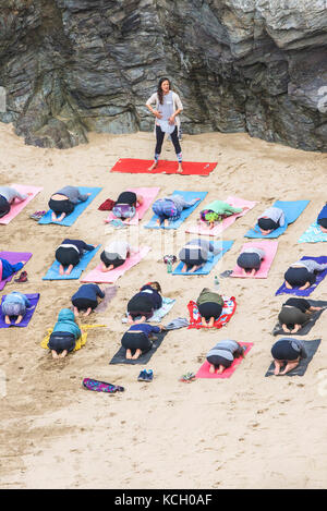 A womens group practising yoga on a beach - Surf Betty’s Festival a festival held in Newquay empowering women through fitness and surfing. Cornwall. Stock Photo
