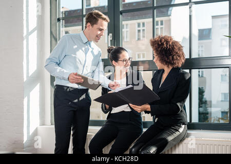 Three young cheerful employees smiling in a modern office Stock Photo