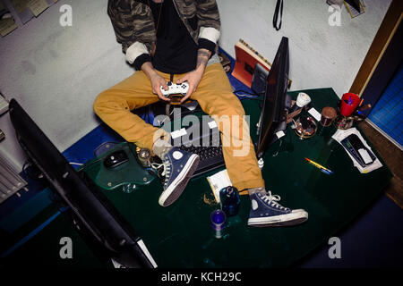 Teenager with video game addiction playing while sitting on a me Stock Photo