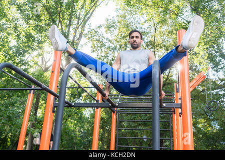 Handsome athletic young man exercising vertical leg raise in an  Stock Photo