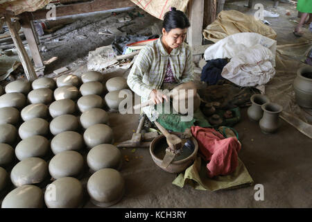 A woman is using a wooden paddle to form pots in Yandabo Village on the Irrawaddy River in Myanmar (Burma). Stock Photo