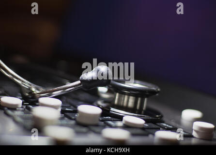 laptop computer keyboard with medicine tablet drugs and medical stethoscope on it Stock Photo