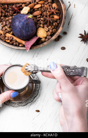 cup of coffee in hands and tongs with cane sugar on a coffee background Stock Photo