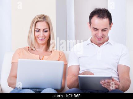 Portrait Of Happy Mid-adult Couple Using Laptop And Digital Tablet Stock Photo