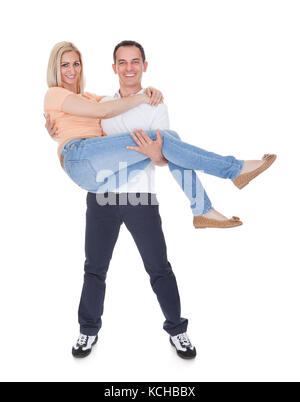 Portrait Of Happy Man Carrying His Girlfriend Over White Background Stock Photo