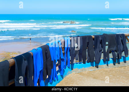 Surf wetsuits drying on the beach. Ericeira, Portugal Stock Photo