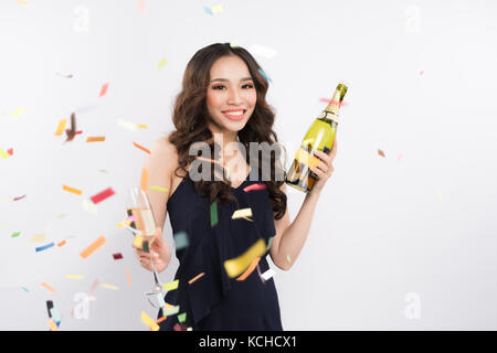 Asian woman celebrating holding wine bottle with confetti on white background Stock Photo
