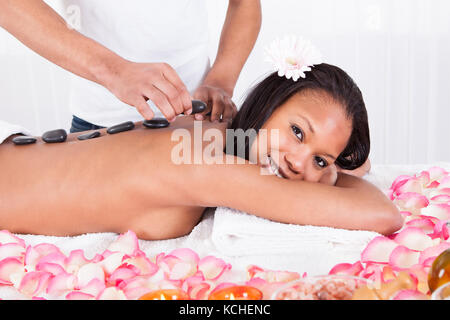 Close-up Of Hand Placing Stone On Woman Back Stock Photo