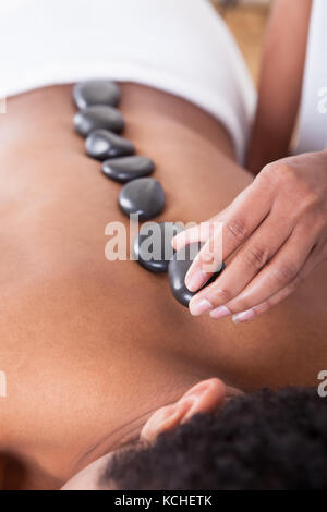 Close-up Of Woman Hand Placing Hot Stone On Man Back Stock Photo
