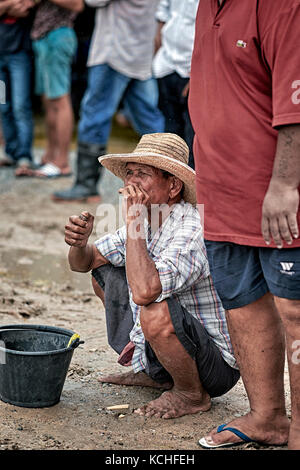 asian squat smoking cigarette Elderly Thailand man squatting and smoking a cigarette. Southeast Asia,  Asian people Stock Photo